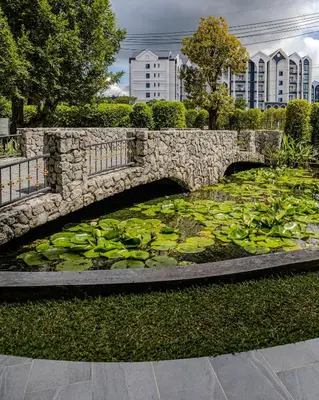 a stone bridge over a pond with lily pads at Cozy studio Pool View near of NaiYang beach in Nai Yang Beach