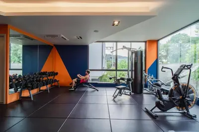 a gym with exercise equipment and a person sitting in a gym at Modern 61m² Apt - Central Chalong/ Fast WiFi in Ban Thalat Choeng Thale