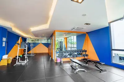 a gym with blue and orange walls and tread machines at Modern 61m² Apt - Central Chalong/ Fast WiFi in Ban Thalat Choeng Thale