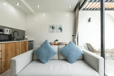 a living room with a couch with two blue pillows at Tropical Holiday Retreat 1BR Villa Near Bangtao in Ban Pak Lak