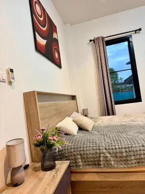 a bedroom with a bed and a window and a vase with flowers at Cozy family cottage w pool Bang Tao in Phuket