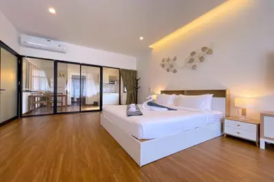 a white bedroom with a large white bed and wooden floors at Goldena Twin Private Villas - Duplex Villa with Sauna, Kamala in Kamala Beach
