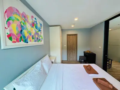 a bedroom with a white bed and a painting on the wall at Comfy studio - 10 min walk to NaiYang Beach in Nai Yang Beach