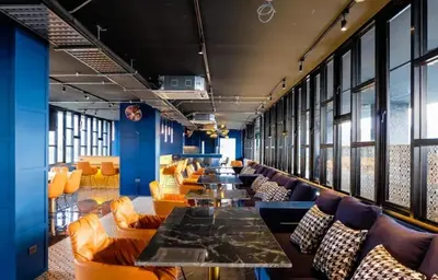 a dining room with couches and tables and windows at Citygate Apartament in Kamala Beach