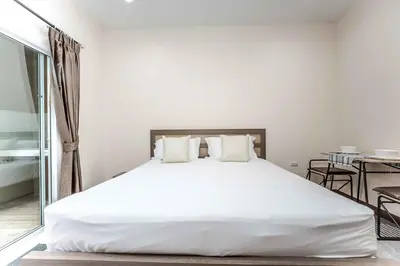 a bedroom with a large white bed with white pillows at RICH house in Ban Thalat Choeng Thale