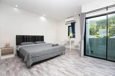 a bedroom with a bed and a large window at Cozy Bonaparte Studios in Ban Thalat Choeng Thale