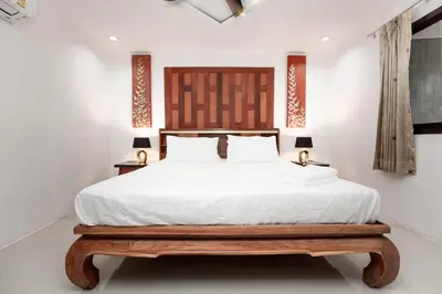 a bedroom with a large white bed with a wooden headboard at Waterfall House, 800 m to the Bang Tao beach in Ban Thalat Choeng Thale