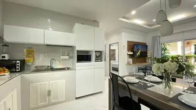 a kitchen with white cabinets and a dining table at Cozy 2-bedrooms houses complex DIN, Bang Tao beach in Ban Thalat Choeng Thale