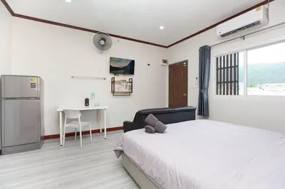 a bedroom with a bed and a refrigerator and a table at DUCATTI apartments, 10 min to Bang Tao beach in Ban Thalat Choeng Thale