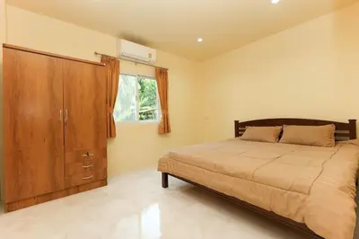 a bedroom with a bed and a wooden cabinet at Yellow apartments 46,47 in Ban Thalat Choeng Thale