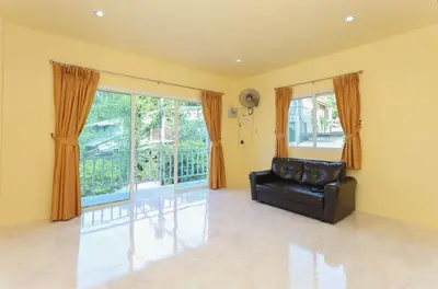 a living room with a leather couch and a large window at Yellow apartments 46,47 in Ban Thalat Choeng Thale