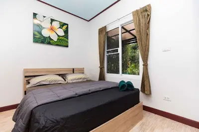 a bedroom with a bed and a window at KUM house in Laguna Phuket