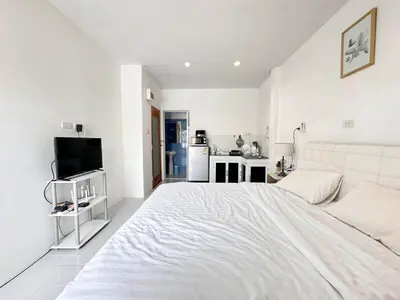 a white bedroom with a large bed and a kitchen at MAM house in a quiet and stylish location in Ban Thalat Choeng Thale
