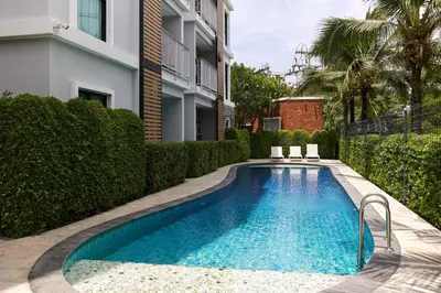 a swimming pool with two chairs next to a building at Cozy Apartment at Rawai with Pool Access in Phuket Town