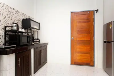 a kitchen with a microwave and a wooden door at Lovely OPTIC apartments on Bang Tao Beach in Ban Thalat Choeng Thale