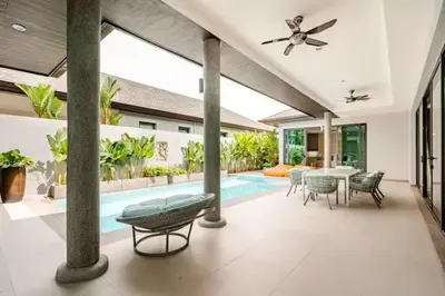 a patio with a table and chairs and a pool at The S Villas in Laguna Phuket