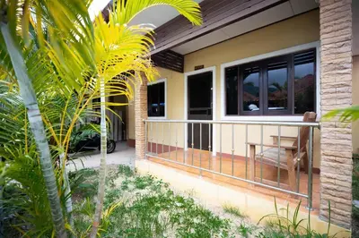a house with a balcony with a table at Cozy PUY houses near Bang Tao Beach in Ban Thalat Choeng Thale