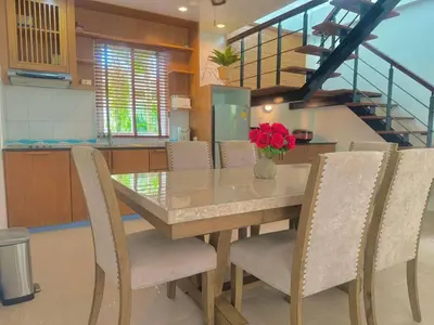 a dining room with a table and chairs and a staircase at Suriyasom Villa 5 in Thalang