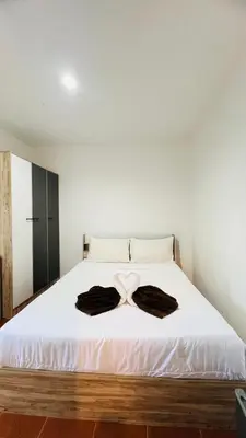 a bedroom with a white bed with two robes on it at Daisy House Patong in Patong Beach