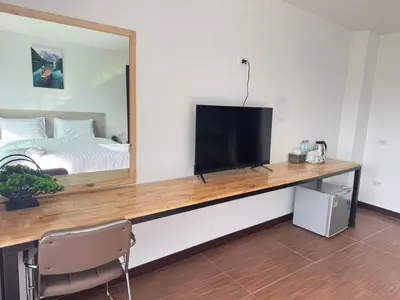 a room with a desk with a television and a bed at Lucky 9 Airport Hotel Phuket in Nai Yang Beach