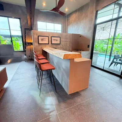 a kitchen with a sink and a counter with stools at Sakhu Art Villa in Nai Yang Beach