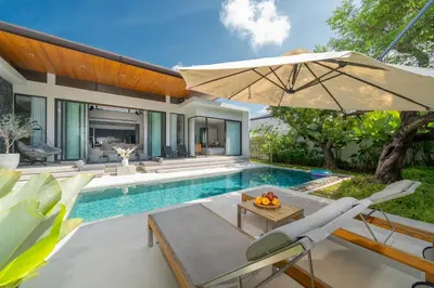 a pool with a table and an umbrella next to a house at Villa Beautiful swimming pool in Phuket