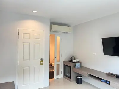 a room with a white door and a tv on the wall at The Sealect Hotel in Kata Beach