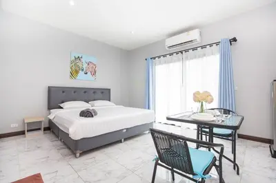 a bedroom with a bed and a desk and a table with a chair at Siam Condo Apartment, 600 metters to Bang Tao beach in Surin Beach