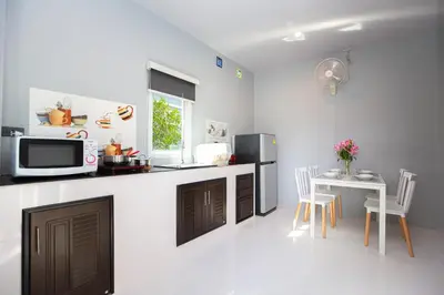 a kitchen with a microwave and a table with chairs at Tutu house, walking distanse to Bang Tao beach in Bang Tao Beach