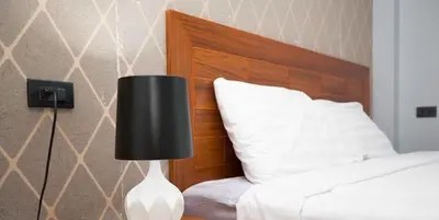a bed with a black lamp next to a white pillow at Tutu house, walking distanse to Bang Tao beach in Bang Tao Beach