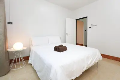 a white bed with a brown towel on top of it at Japanese barnhouse Bang Tao beach in Ban Thalat Choeng Thale