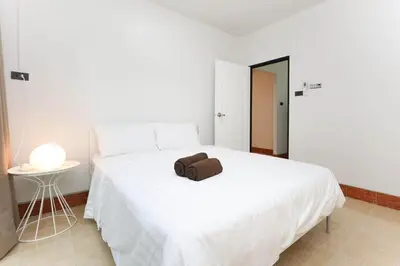 a white bed with a brown towel on top of it at Japanese barnhouse Bang Tao beach in Ban Thalat Choeng Thale