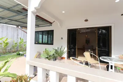 a balcony of a house with chairs and a table at Japanese barnhouse Bang Tao beach in Ban Thalat Choeng Thale