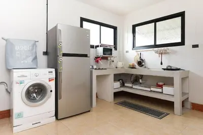 a kitchen with a refrigerator and a washing machine at Japanese barnhouse Bang Tao beach in Ban Thalat Choeng Thale