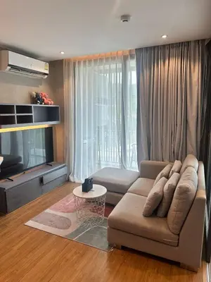 a living room with a couch and a tv at CityGate Kamala 1 bedroom by Ere L807 in Kamala Beach