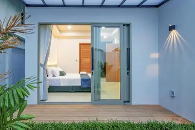 a glass door leading to a bedroom with a bed at Phirunda Pool Villas in Ban Suan