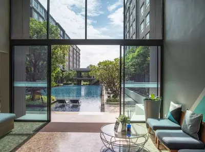 a living room with a view of a pool through windows at Valley Mountain View&City Proximity Golden Eight Apartment in Ban Phlu Yai
