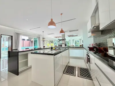 a kitchen with white cabinets and black counter tops at Kamala Seaview - 3 BR Private Pool Villa in Kamala Beach