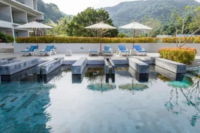 a swimming pool with chairs and umbrellas next to a building at The Ark Karon Beach by RESAVA in Karon Beach
