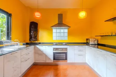 a kitchen with white cabinets and an orange wall at V265 2BR Pool Villa Near Fitness Gyms Muay Thai in Ban Saiyuan (1)