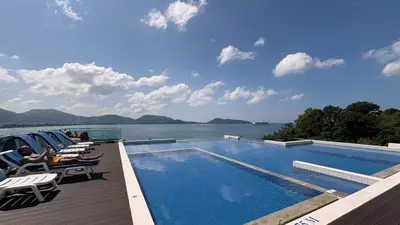 a swimming pool with chairs and a view of the water at The Privilege by Tris in Patong Beach