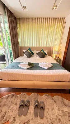 a bedroom with a bed with two pairs of shoes on the floor at The Privilege by Tris in Patong Beach