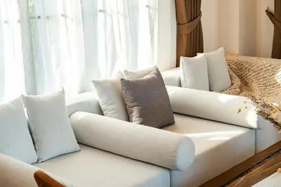 a white couch with pillows on it next to a window at Phu Talae Villa Rawai Beach in Ban Klang