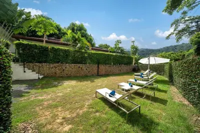 three lounge chairs and an umbrella in a yard at Oxavia Garden Bungalow B1 -B2 Nai Harn in Rawai Beach