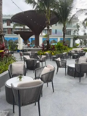 a patio with chairs and tables and palm trees at Sunshine Beach, Kora Resort Phuket 5, Bang Tao, Laguna in Bang Tao Beach