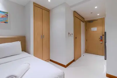 a bedroom with a bed and two wooden doors at C244 Ocean Breeze 1BR Studio Steps from the Sea in Ban Saiyuan (1)
