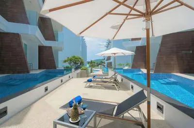 a pool with an umbrella and chairs and a table with an umbrella at C245 Steps from the Beach Pool & Ocean View in Ban Saiyuan (1)