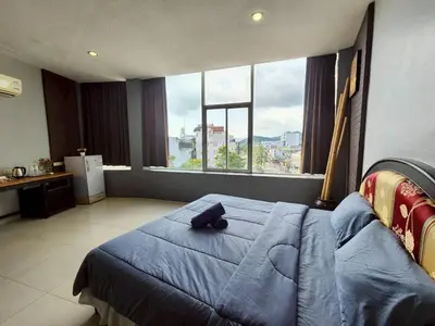 a bedroom with a blue bed and a large window at The Rest Phuket in Phuket Town