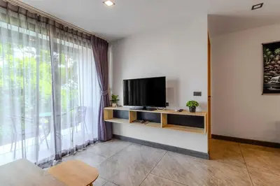a living room with a tv and a large window at C248 Condo 3 Min to Nai Harn Beach 1BR with Rooftop Pool in Rawai Beach