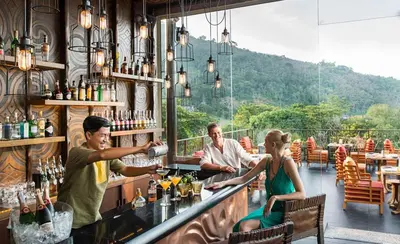 a group of people sitting at a bar at Keemala - Tree Pool House in Kamala Beach
